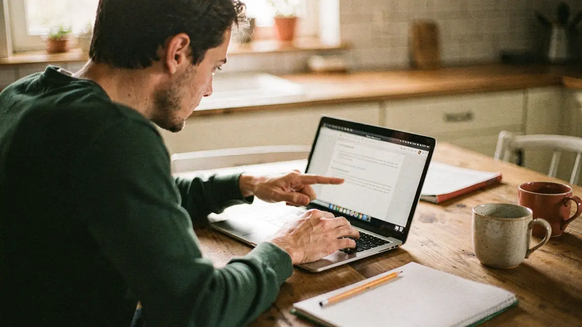 Two people at a kitchen table building a website on a laptop during a workshop session
