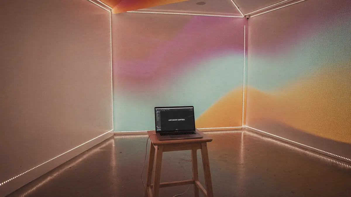 An immersive room washed in projected color with LED runs along every edge, driven by a laptop